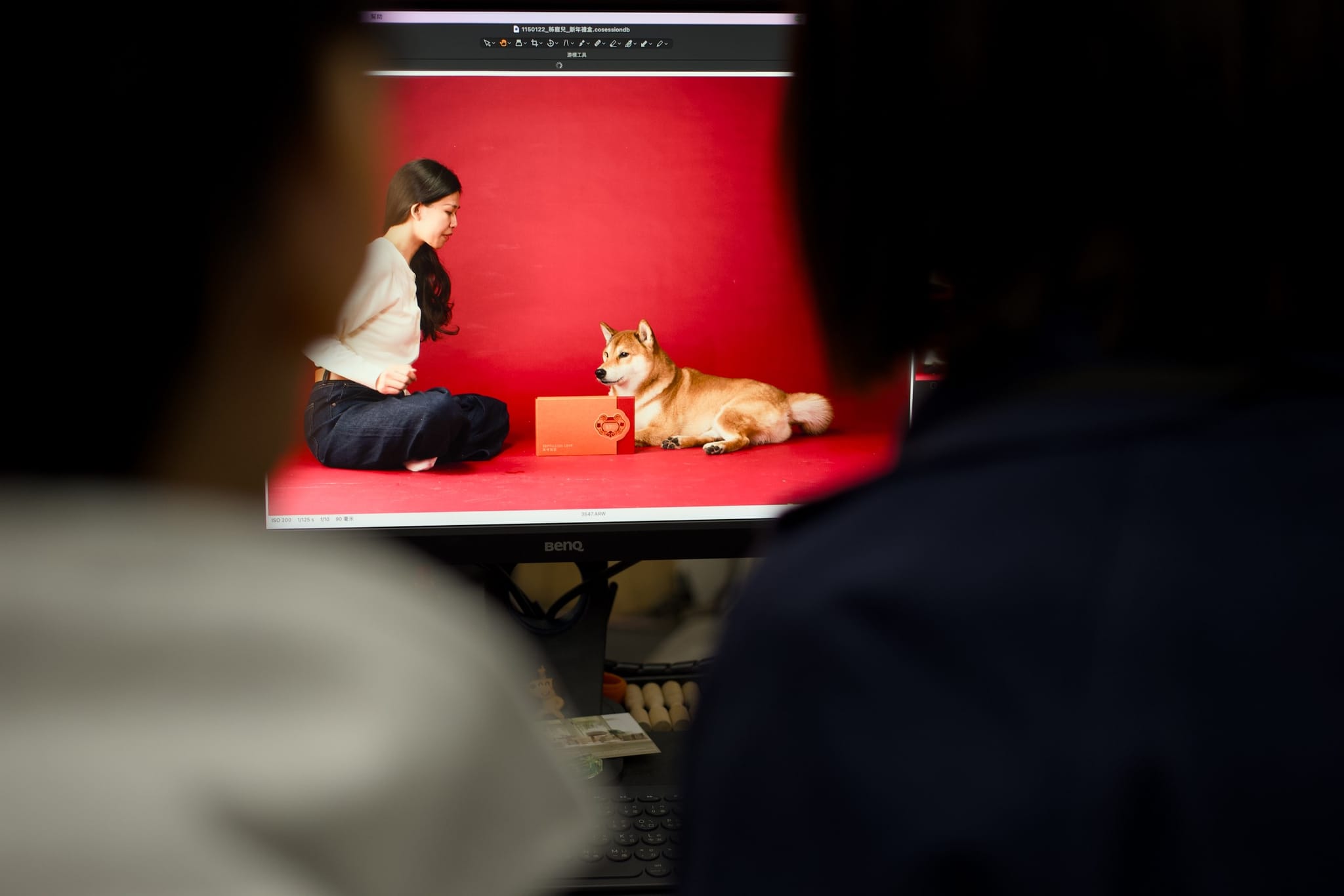 負責人透過螢幕畫面，細心確認柴犬與禮盒的攝影構圖與光線，確保影像品質。