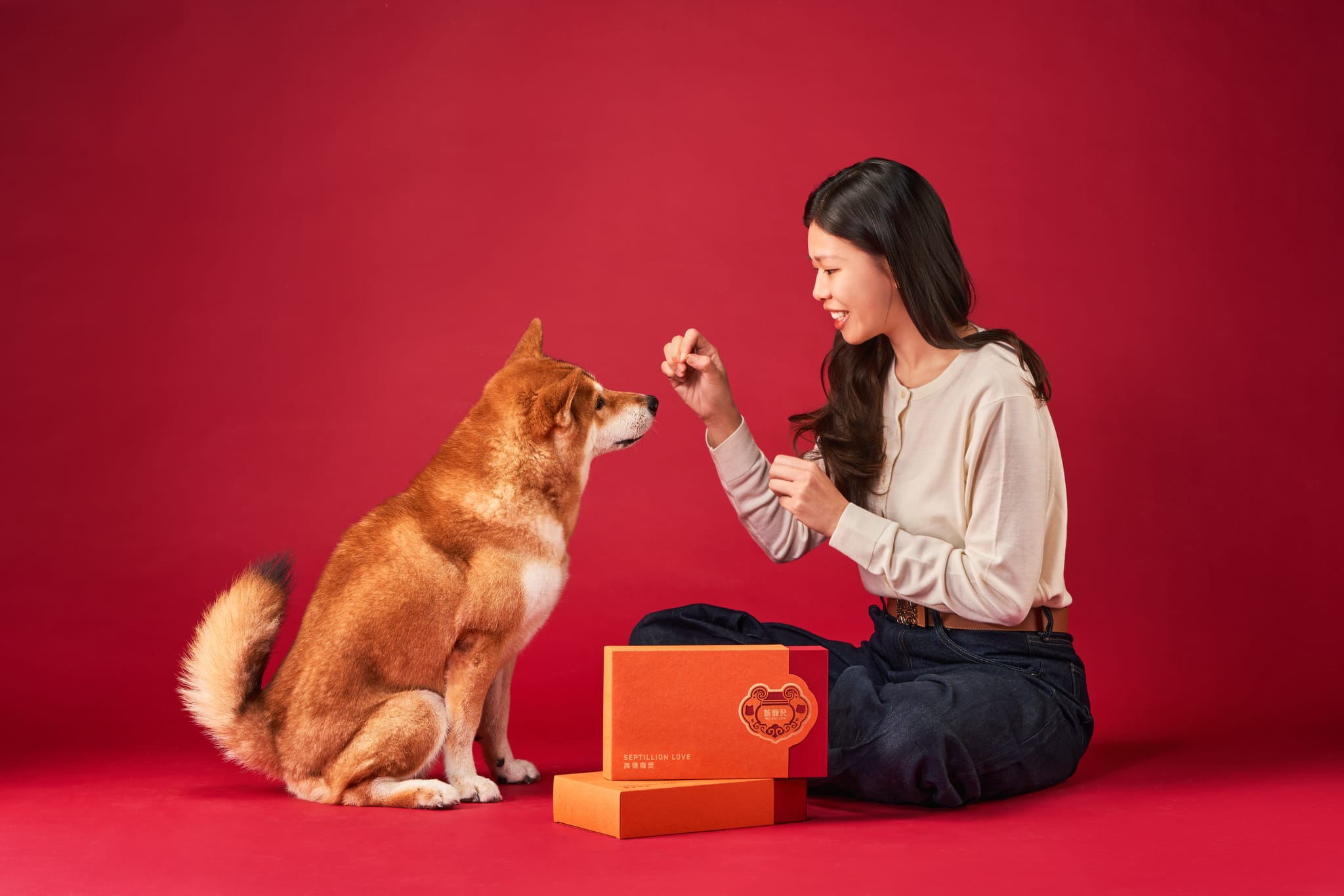飼主與毛孩在紅背景前，新春限定禮盒上印有平安鎖圖案。