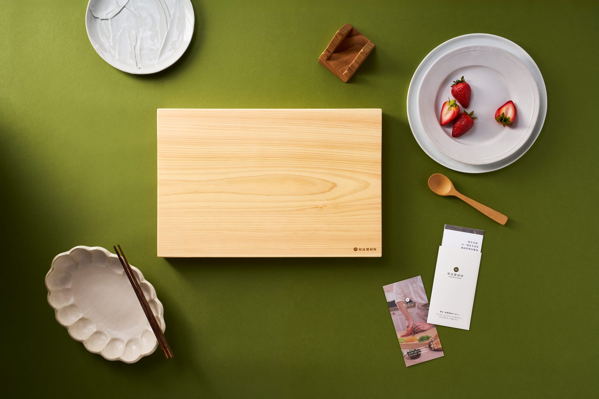餐桌上的日本檜木砧板，搭配餐具與新鮮草莓，呈現實木廚具的溫潤美感。