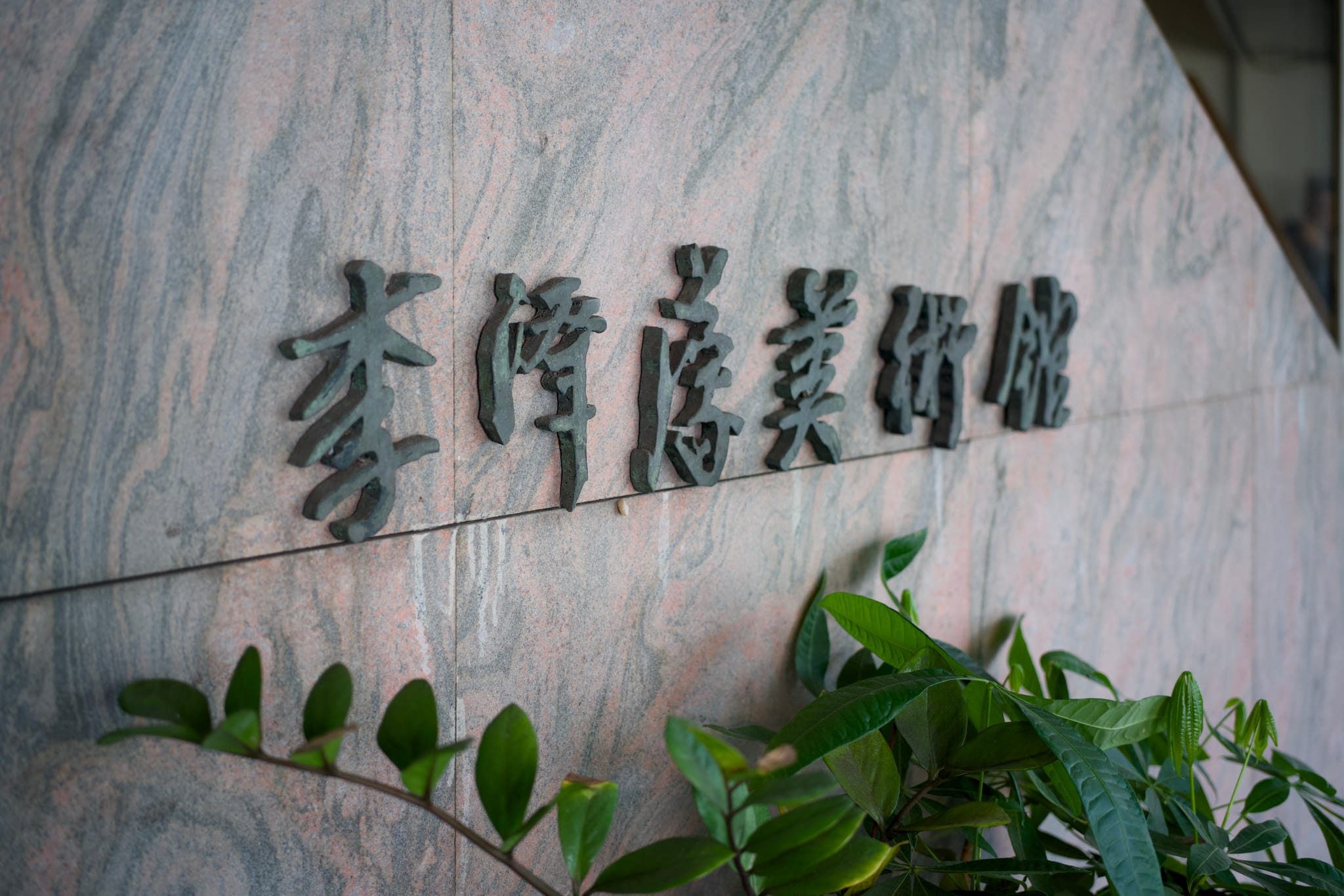 李澤藩美術館入口處的石牆招牌，綠葉點綴其下，彰顯著本次藝術對話的場地。