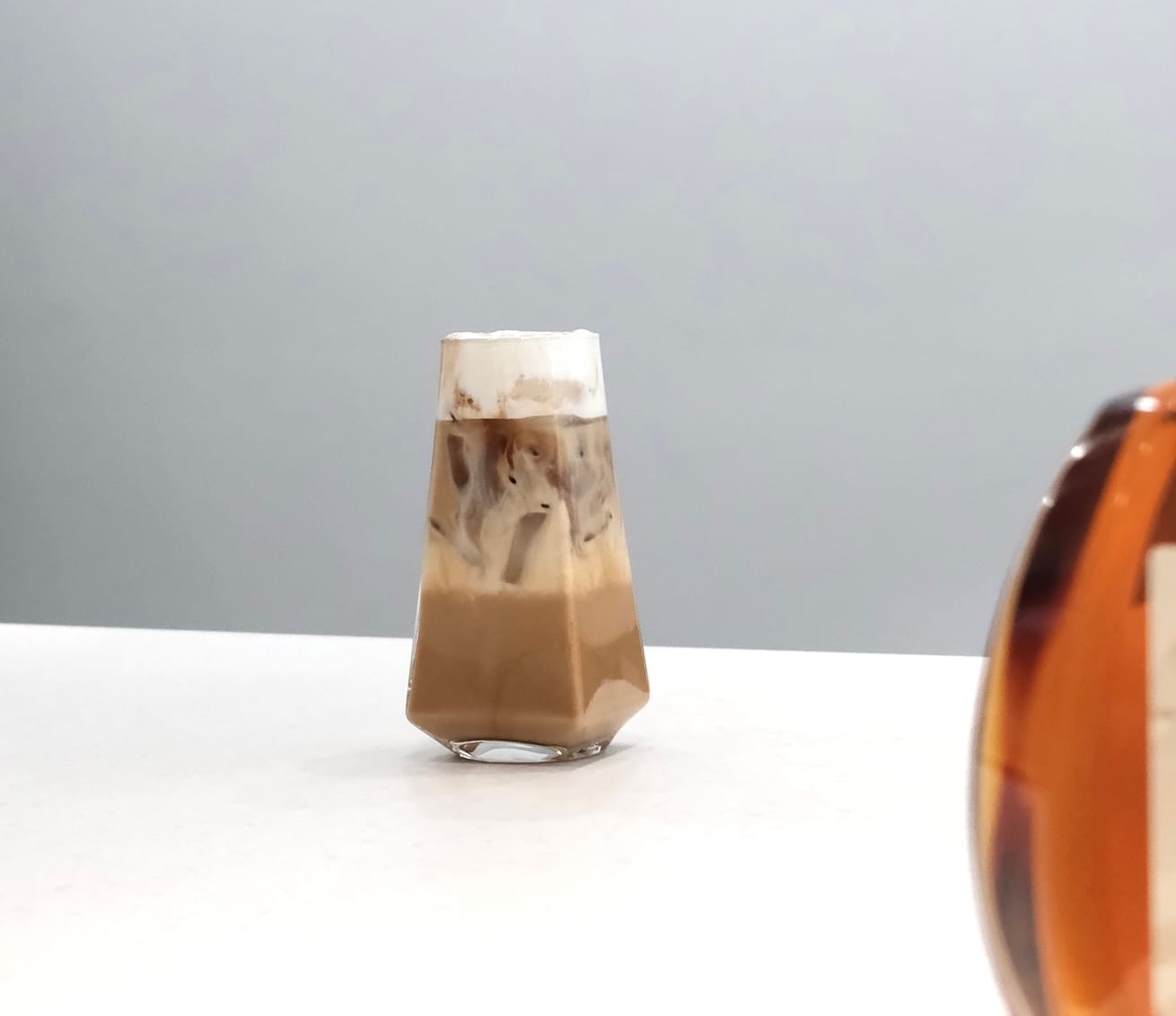 一杯綿密泡沫的白蘭地咖啡，與琥珀色干邑酒瓶，聯名呈現。