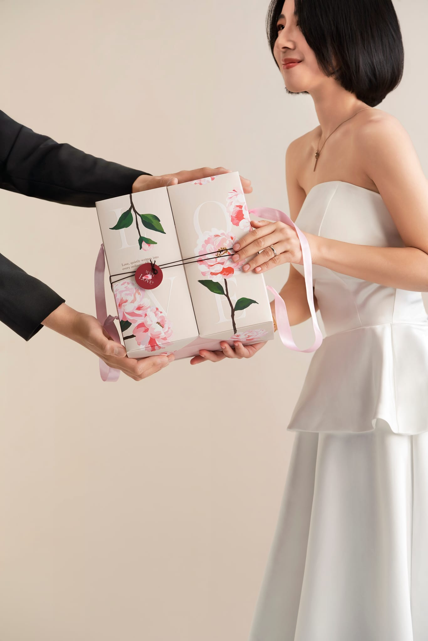 新娘接過純淨米白色、飾有蝴蝶陸蓮圖案的蒙恩花序喜餅。