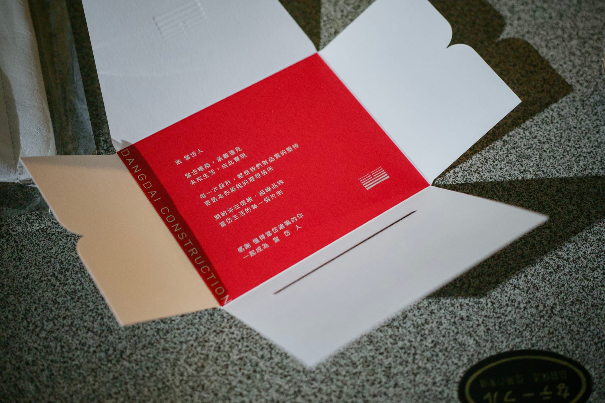 紅白色交屋盒展開，露出內襯「DANGDAI CONSTRUCTION」字樣，營造精品開箱感。