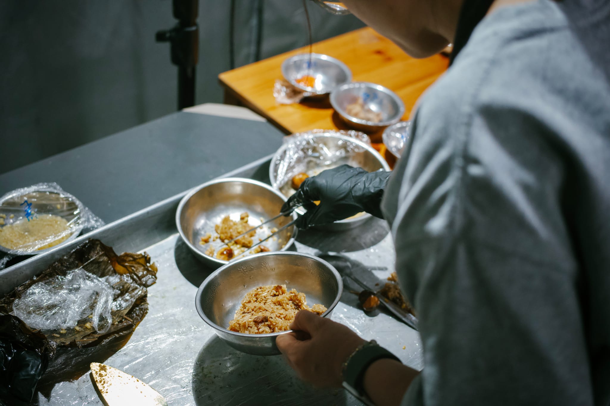 攝影師戴手套，將蒸熟的粽子拆解後重組，呈現食材原貌。