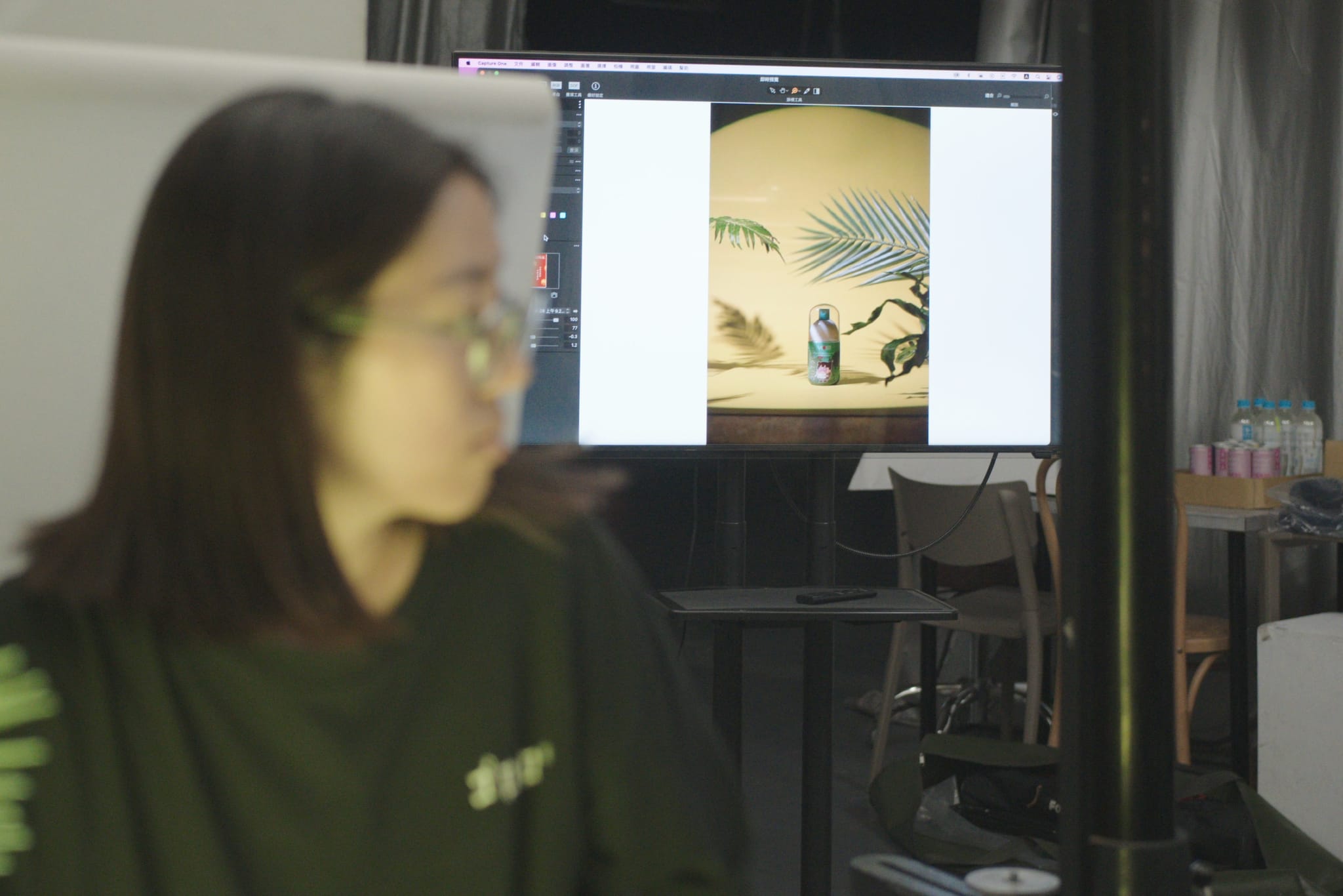 攝影師林巾郁在螢幕前檢視薇佳防曬噴霧產品照，畫面中展示了真實植栽的背景佈置。