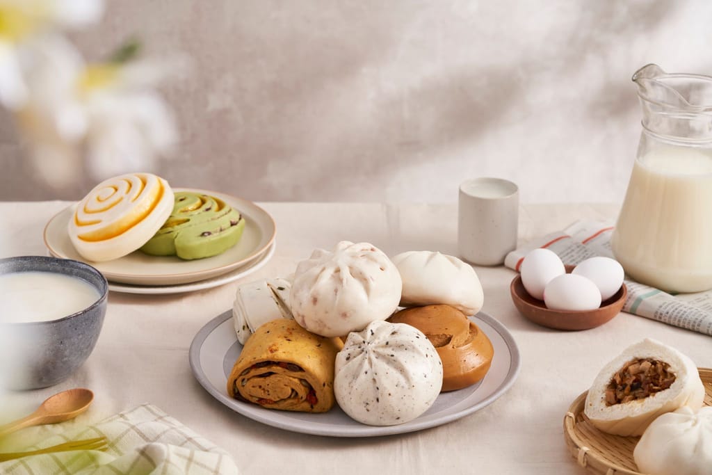 小日和官網形象：溫馨餐桌上擺放多種手工包子、饅頭、牛奶與雞蛋，展現品牌日常真誠。