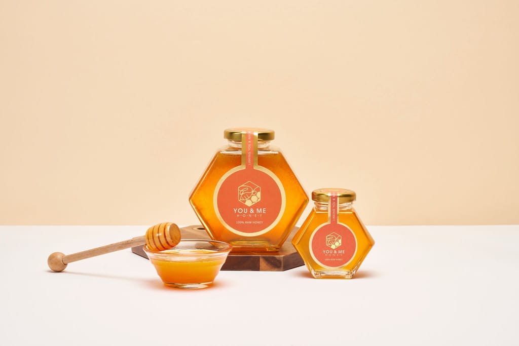 優蜜純生蜂蜜禮盒情境：大小蜂巢瓶蜂蜜、蜜勺與盛蜜小碗。