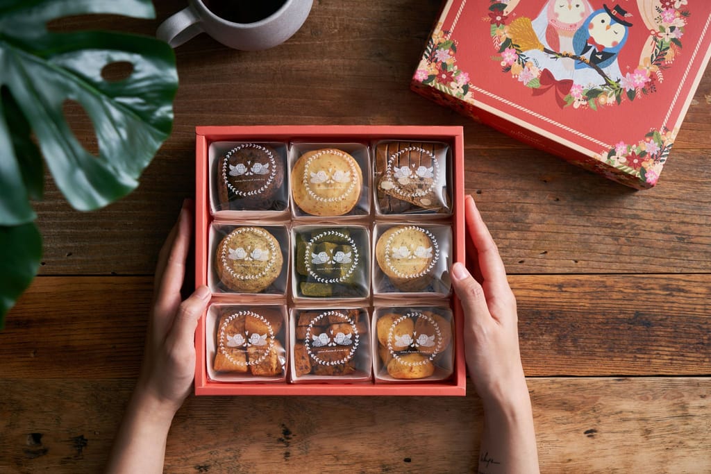 一雙手捧著「點心魔法師」手工喜餅禮盒，在溫馨情境中展現真誠心意。