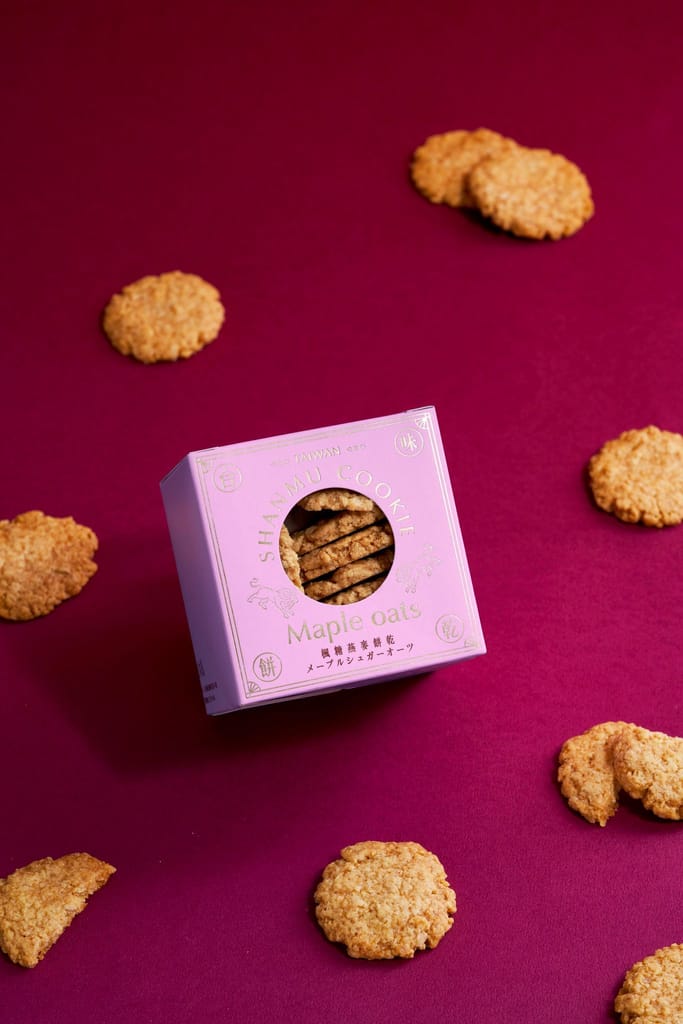 山木島楓糖燕麥餅乾粉色盒裝單品情境，餅乾散落在紫紅色背景上。