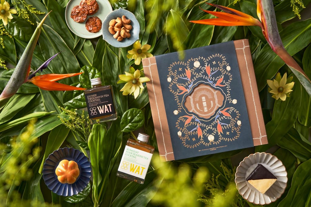 喜豐香1985新年禮盒，精緻點心與WAT雞尾酒，置於翠綠葉片與花朵間，展現新年喜慶與品牌質感。