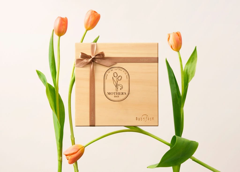 木質母親節禮盒繫棕色緞帶，周圍點綴橘色鬱金香，溫馨雅緻。