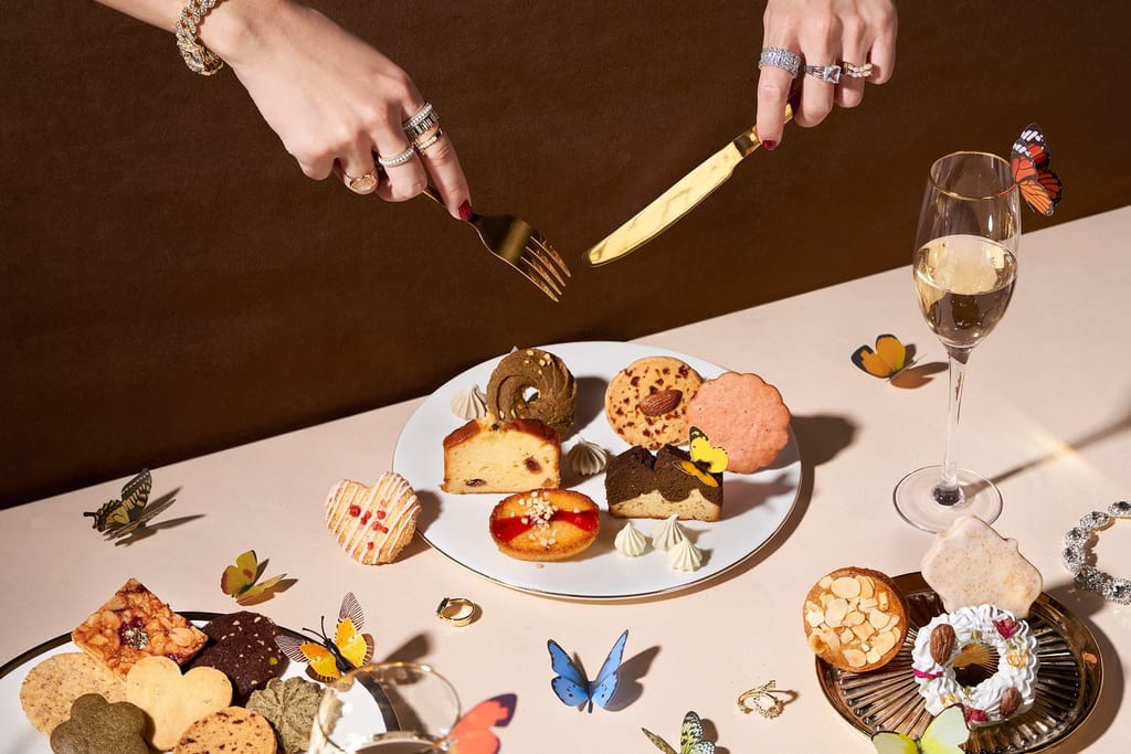 花神頂級甜點的精緻擺盤，雙手優雅取用，蝴蝶與香檳相伴，展現品牌奢華與真誠的品味生活。