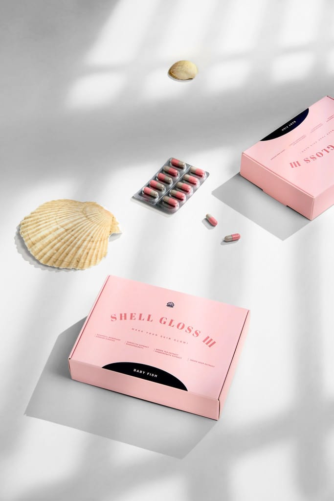 粉色貝光 lll 食品膠囊包裝盒與膠囊，點綴貝殼，光影營造純淨感。