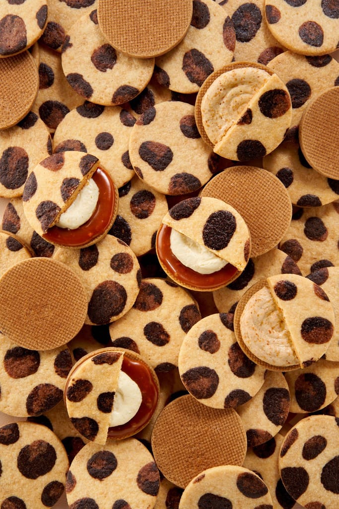 特寫石虎斑紋餅乾堆疊，部分切面露出焦糖與奶油內餡，夾雜圓形格紋餅乾。