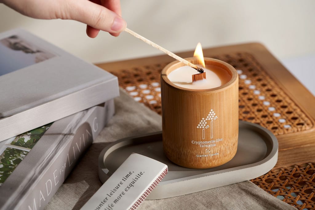 手持火柴點燃竹筒蠟燭，呼應「解碼山林」的自然意象。