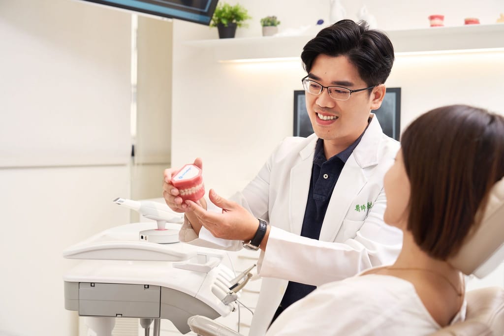 牙醫師親切地向患者解釋牙齒模型，展現專業與真誠的醫病互動。