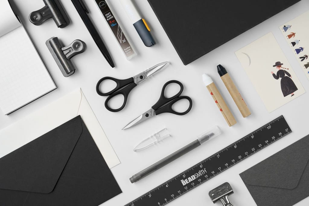 整齊排列的黑白色系文具用品，包含剪刀、筆、尺、夾子與信封，呈現簡潔專業感。