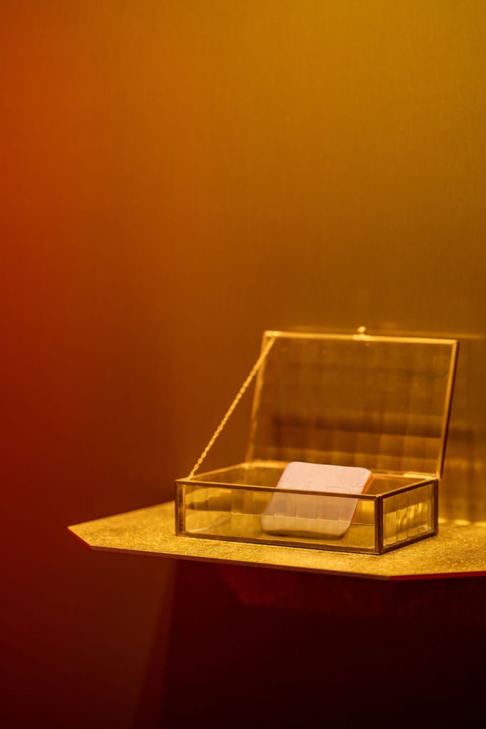 喜餅體驗空間中，暖光下的透明玻璃盒內放置精緻物件。