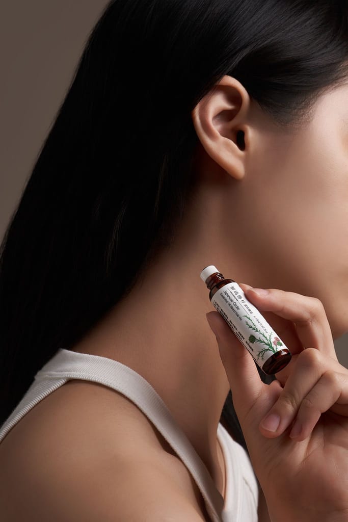 女性優雅地手持全方位保養油，輕置於頸間，展現產品的溫和觸感。