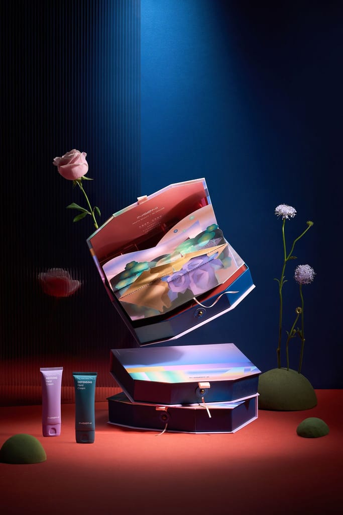 動態構圖呈現打開的六角形美手霜禮盒、兩支手霜與花朵，光影營造夢幻氛圍。