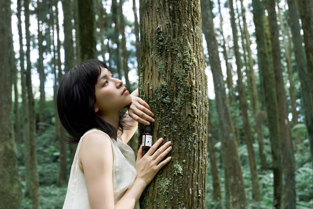 淨保養系列於山林間拍攝，女子輕撫樹幹，感受自然氣息與產品連結。