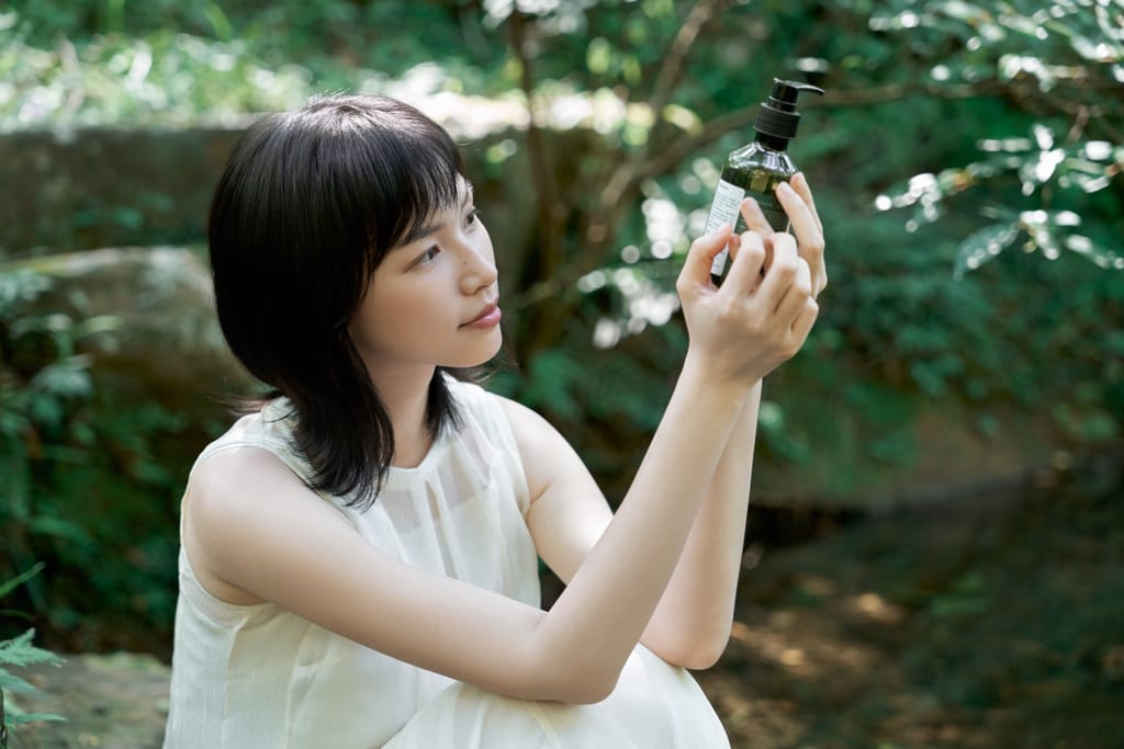 女性於森林中檢視著產品，體現淨保養與台灣山林氣味的連結。