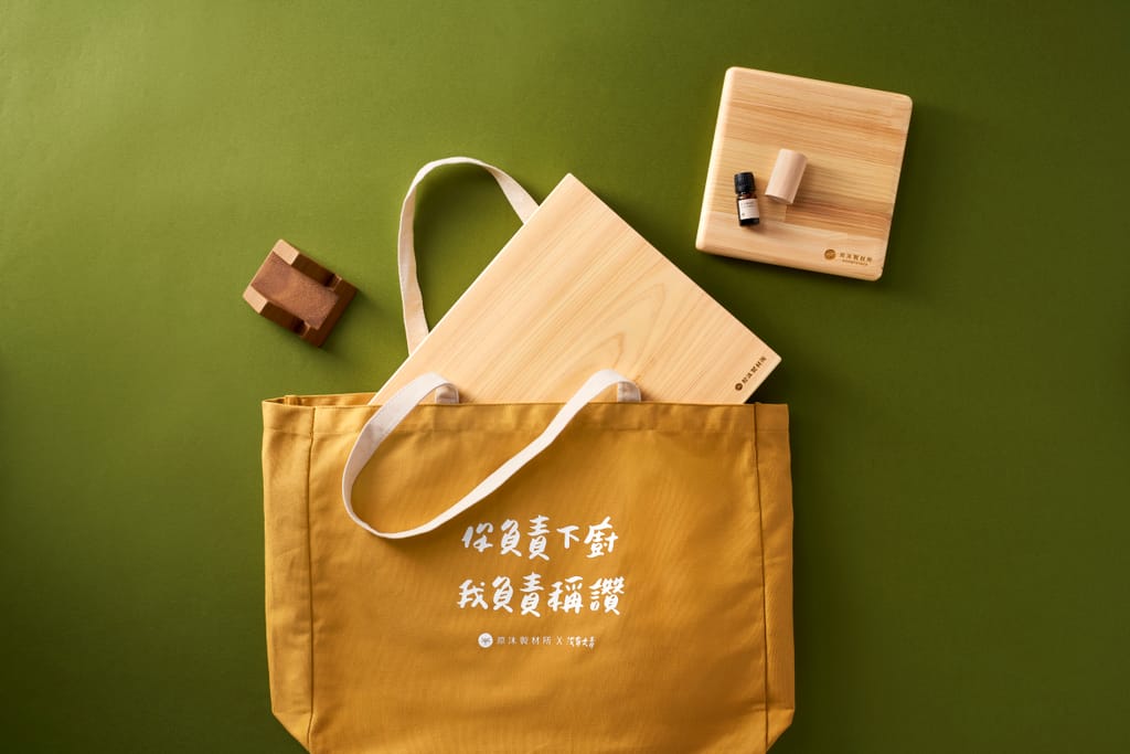 陳列著兩塊檜木砧板、精油瓶，搭配黃色帆布袋，傳達木製品的生活美學與永續理念。