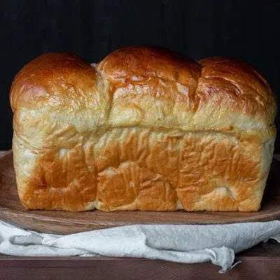 une brioche entière posée sur une assiette en bois