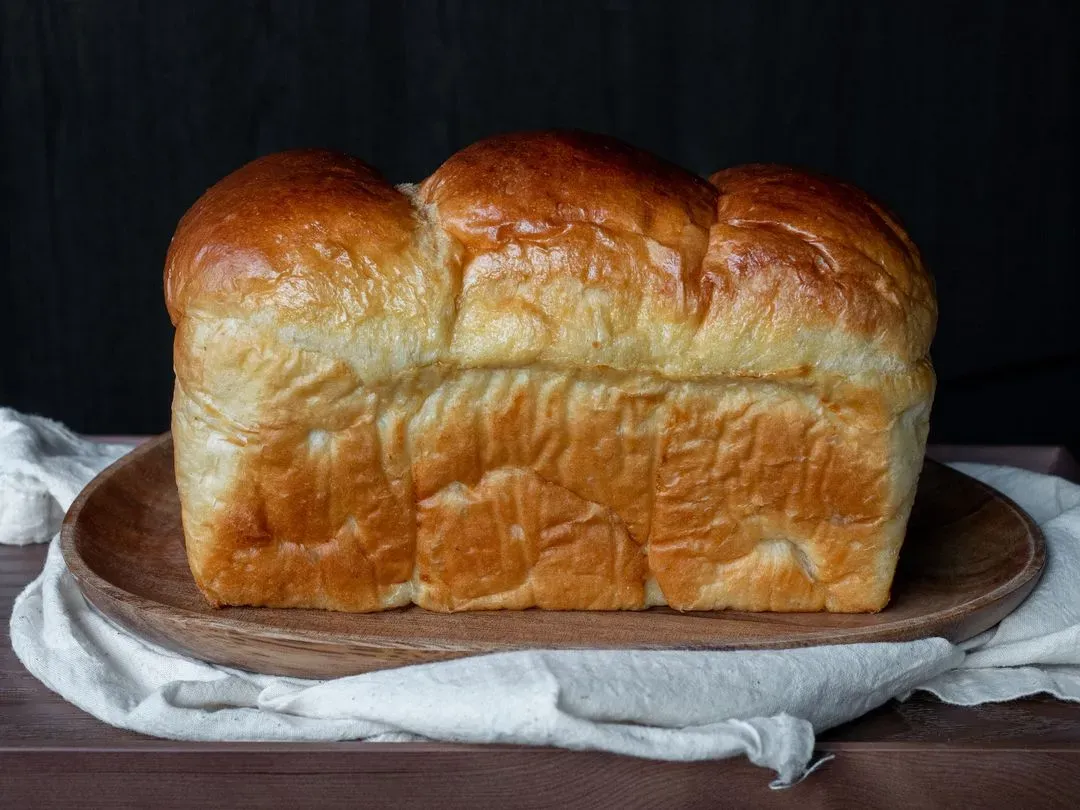 une brioche entière posée sur une assiette en bois