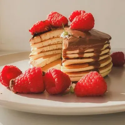 Une pile de pancakes sur lequel on verse du sirop d'érable 