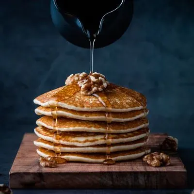 Une pile de pancakes sur lequel on verse du sirop d'érable 