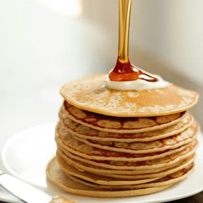 une pile de pancakes avec du sirop d'érable qui coule sur le dessus