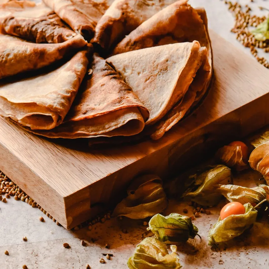 Crêpes pliées en triangles et empilées sur une planche en bois