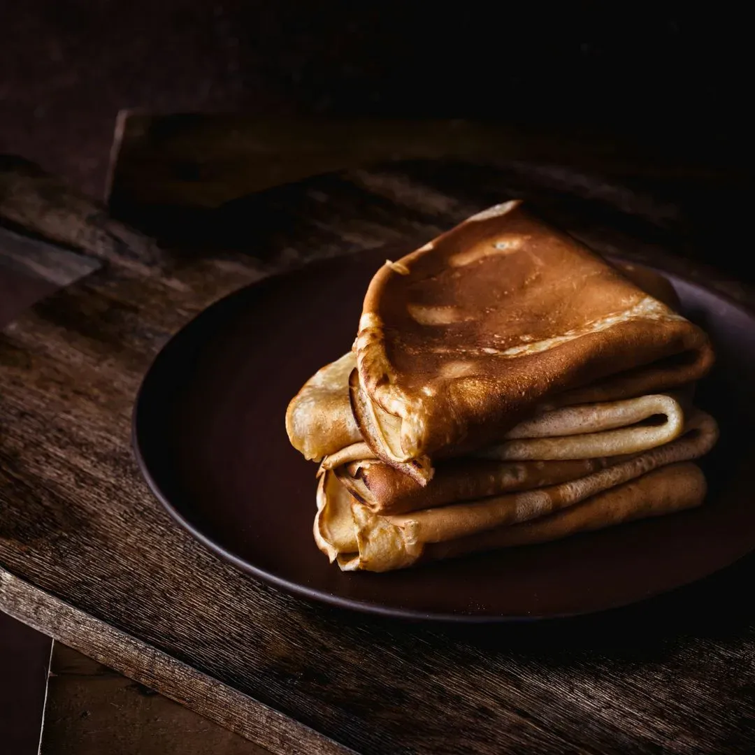 des crêpes pliées e quatres sur un plan de travail en bois