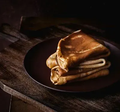 des crêpes pliées e quatres sur un plan de travail en bois