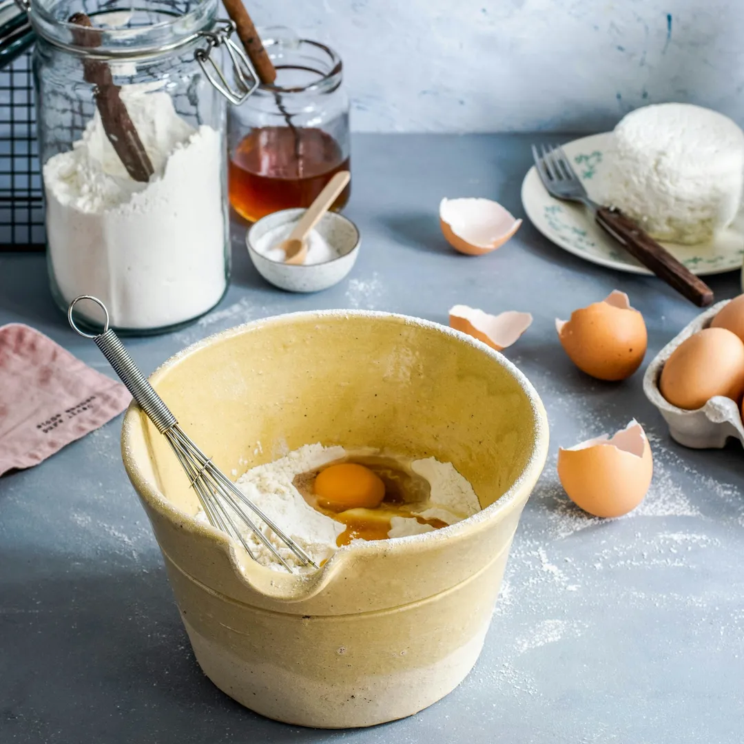 un bol avec les ingrédients pour faire des crêpes sur un plan de travail