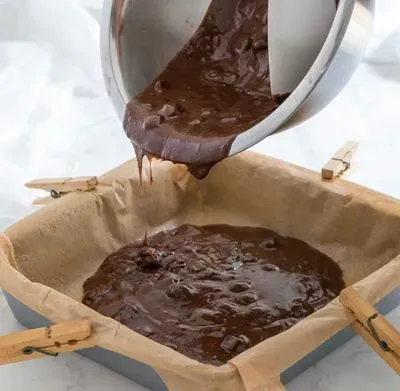 une personne qui met la pâte à gateau au chocolat dans un moule