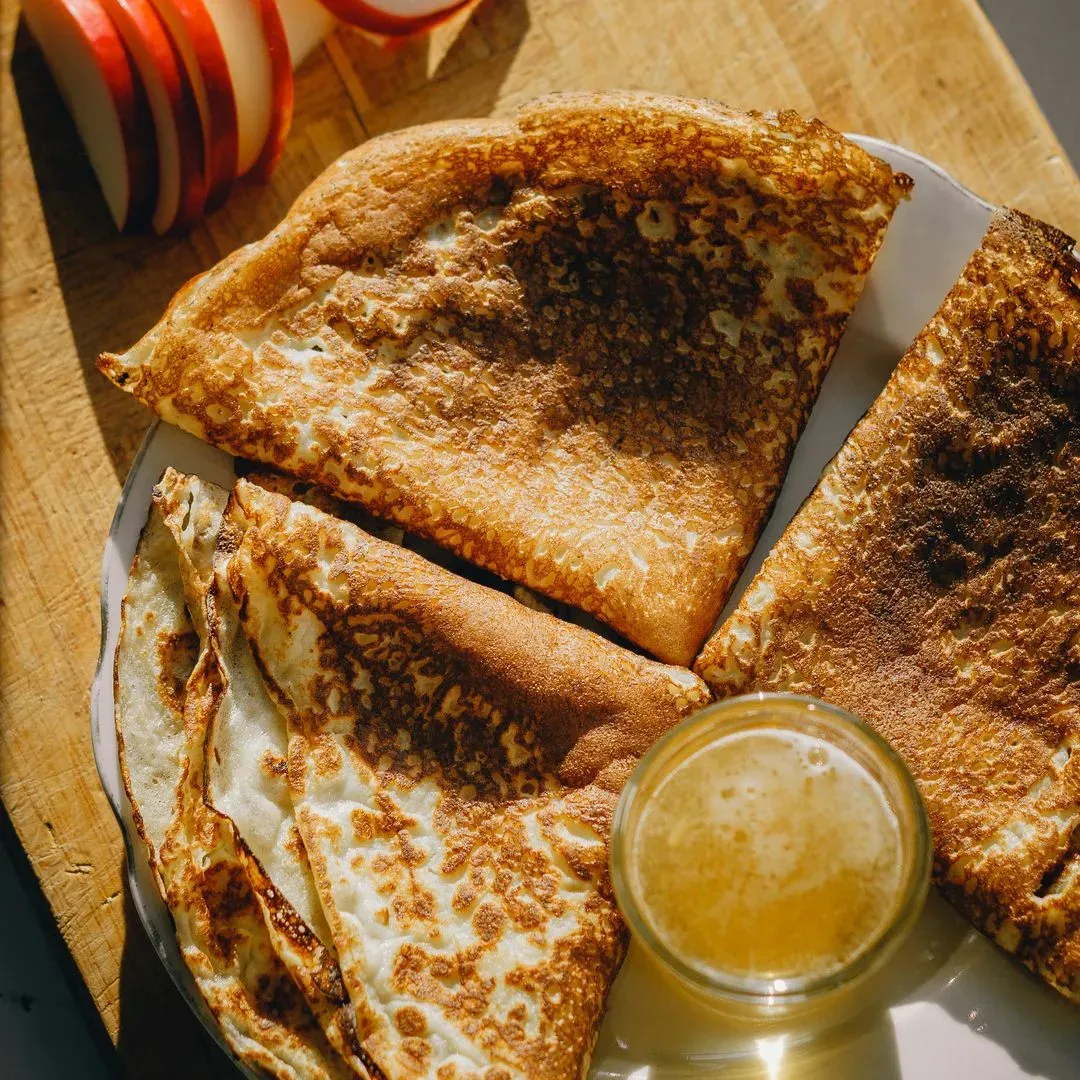 des crêpes pliées sur une assiette avec des fruits