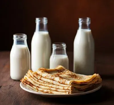 des crêpes pliées sur une assiette des plusieurs types de lait à côté