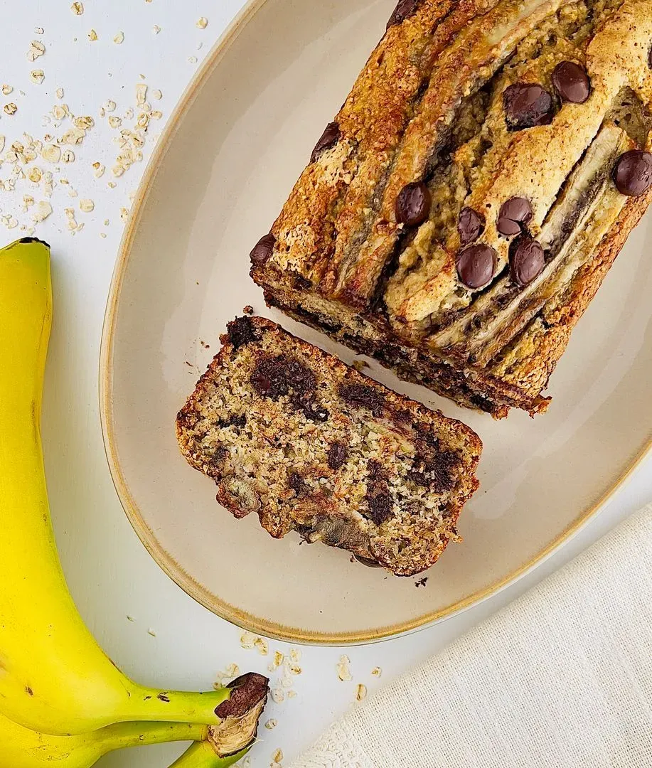 un banana bread aux flocons d'avoine et chocolat sur un plat avec des parts coupées