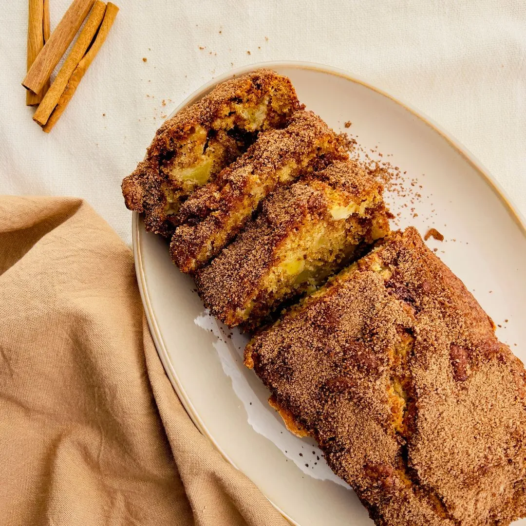 Un cake pommes cannelle sur un plat avec deux parts coupées