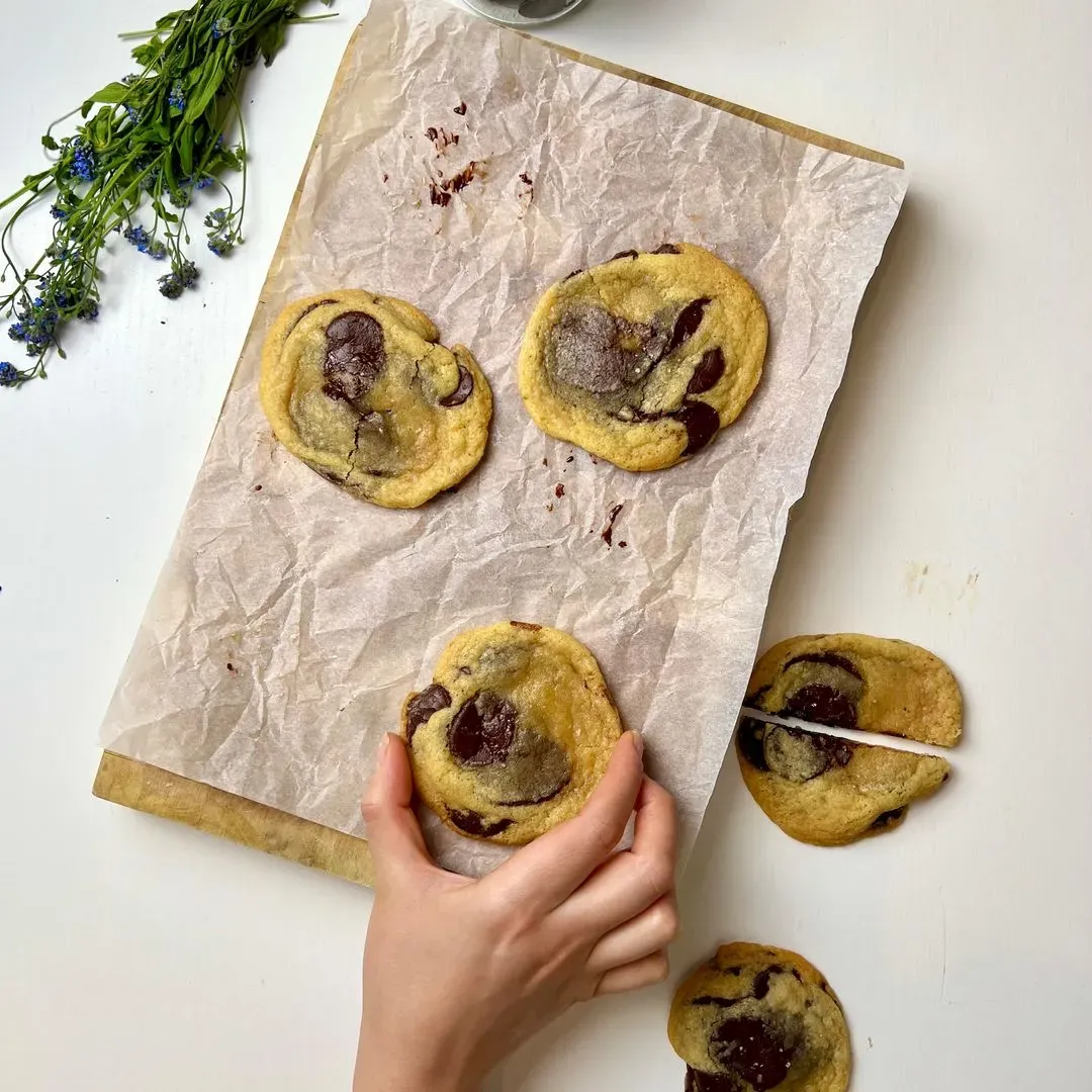 Une personne dépose des cookies aux pépites de chocolat sur une feuille de cuisson