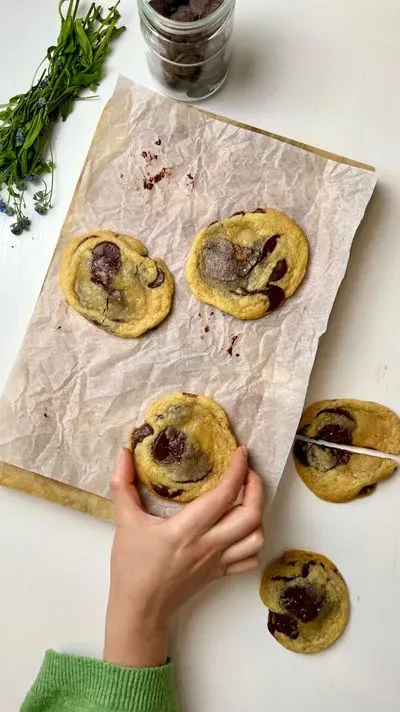 Une personne dépose des cookies aux pépites de chocolat sur une feuille de cuisson