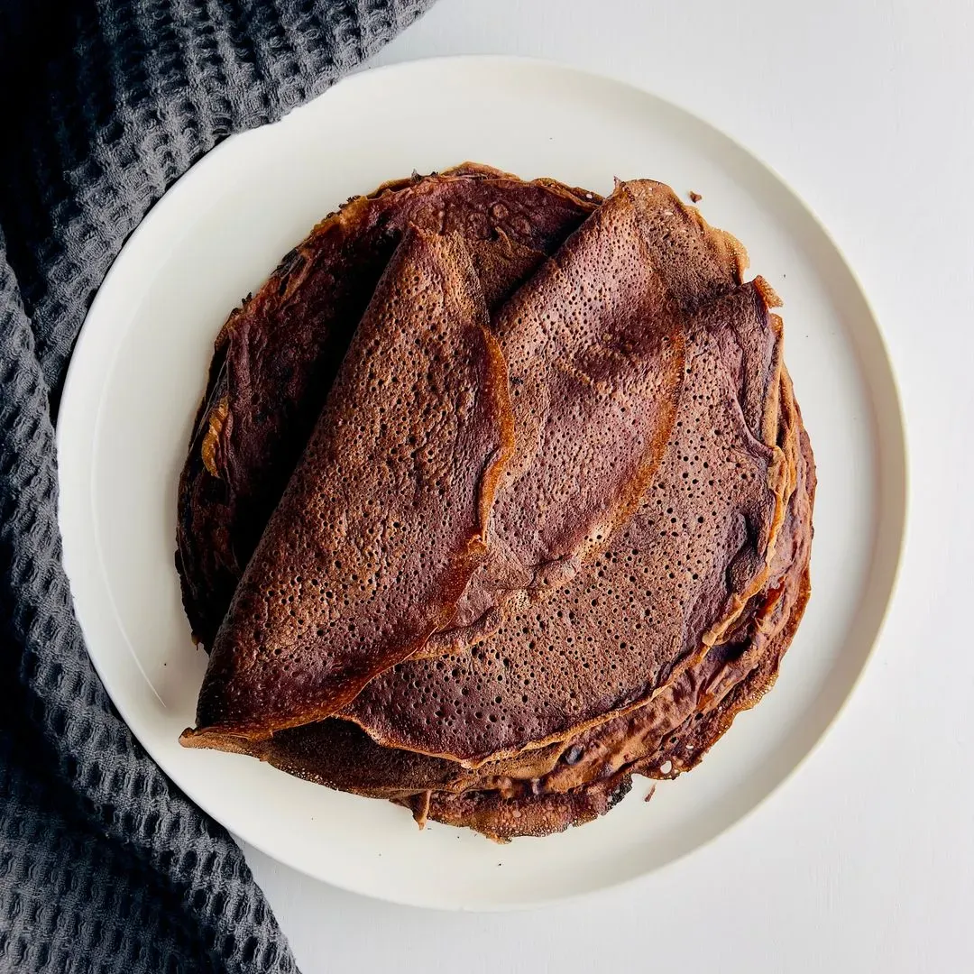 des crêpes au chocolat empilées sur une assiette blanche