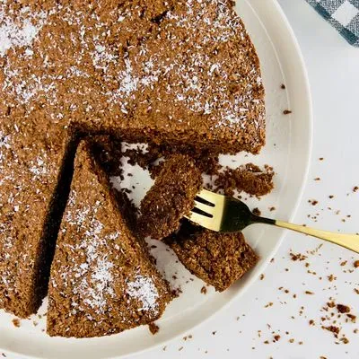 un gateau chocolat et noix de coco sur une assiette blanche avec une part coupée