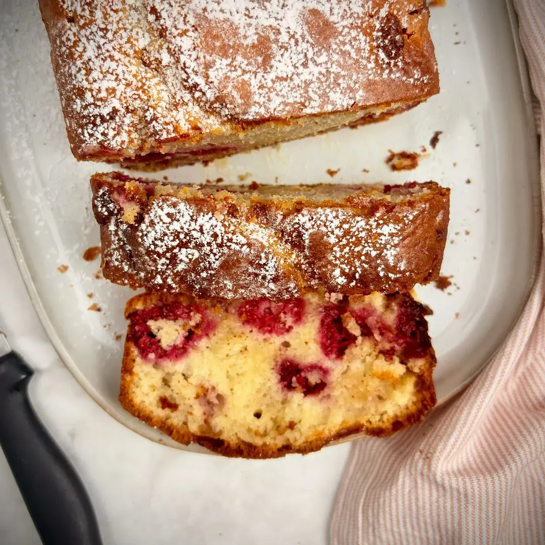 Gâteau au yaourt, framboises et chocolat blanc vue d'en haut d'un gateau yaourt framboise chocolat blanc avec une part coupé