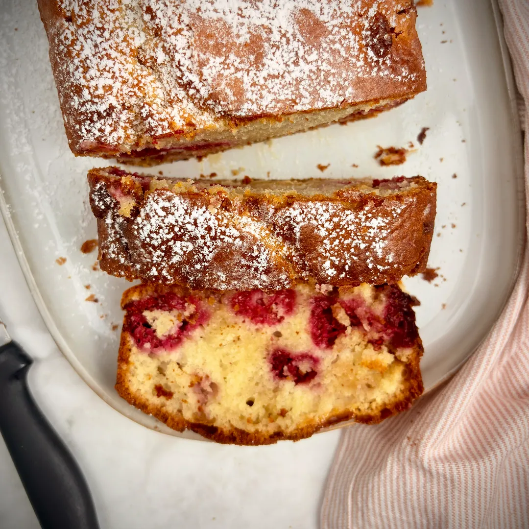 vue d'en haut d'un gateau yaourt framboise chocolat blanc avec une part coupé