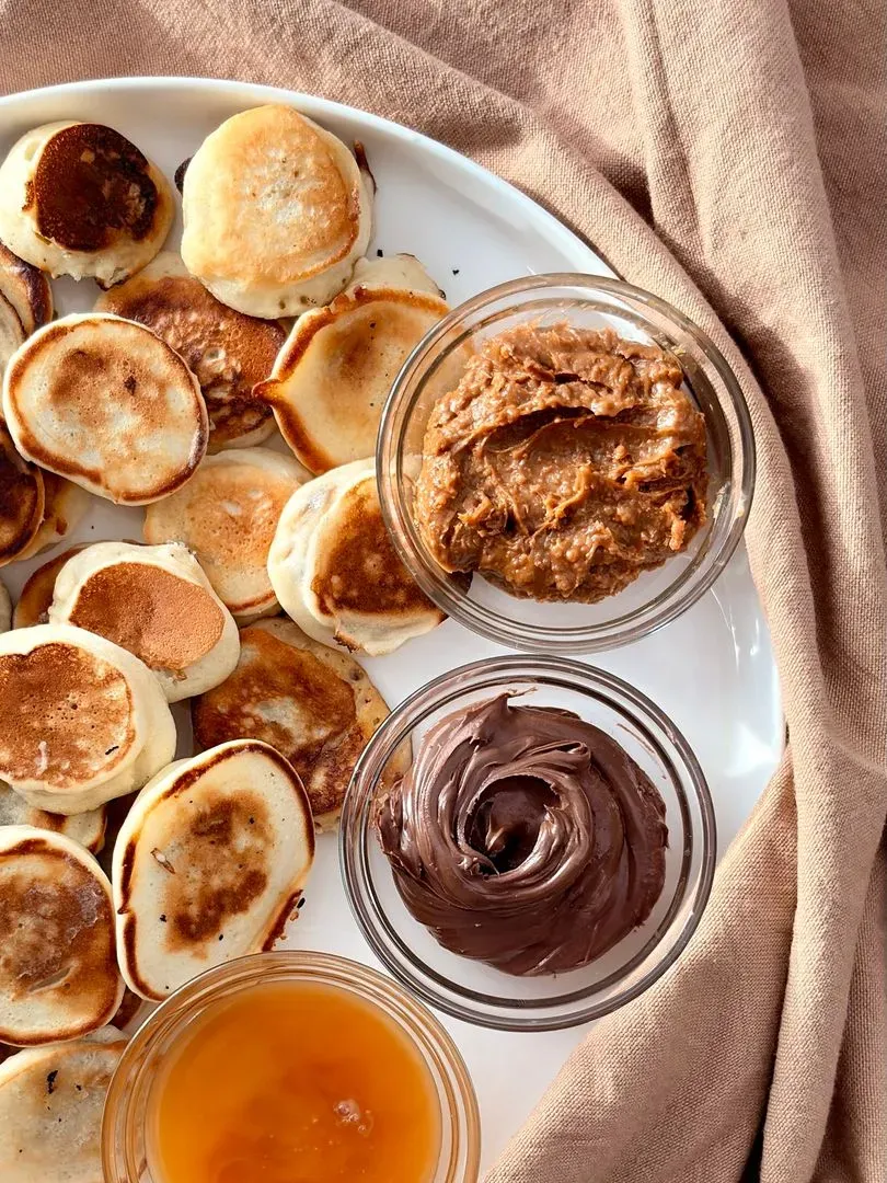 des mini pacakes banane avec des petits pot de nutella, miel et pâte de speculoos a côté
