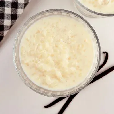 du riz au lait dans un ramequi, avec 2 gousses de vanille à côté