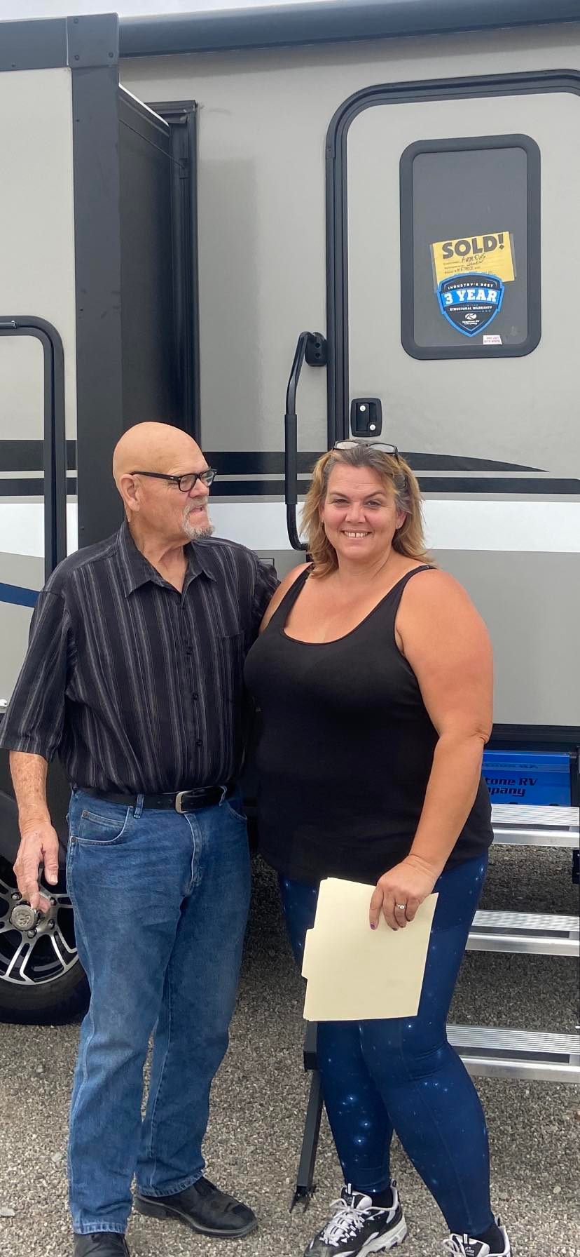 Kat standing with a man in front of a recreational vehicle.